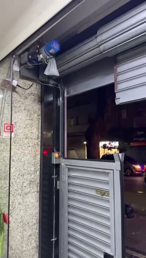Equipe posicionando a cortina de aço durante a instalação de porta de enrolar comercial