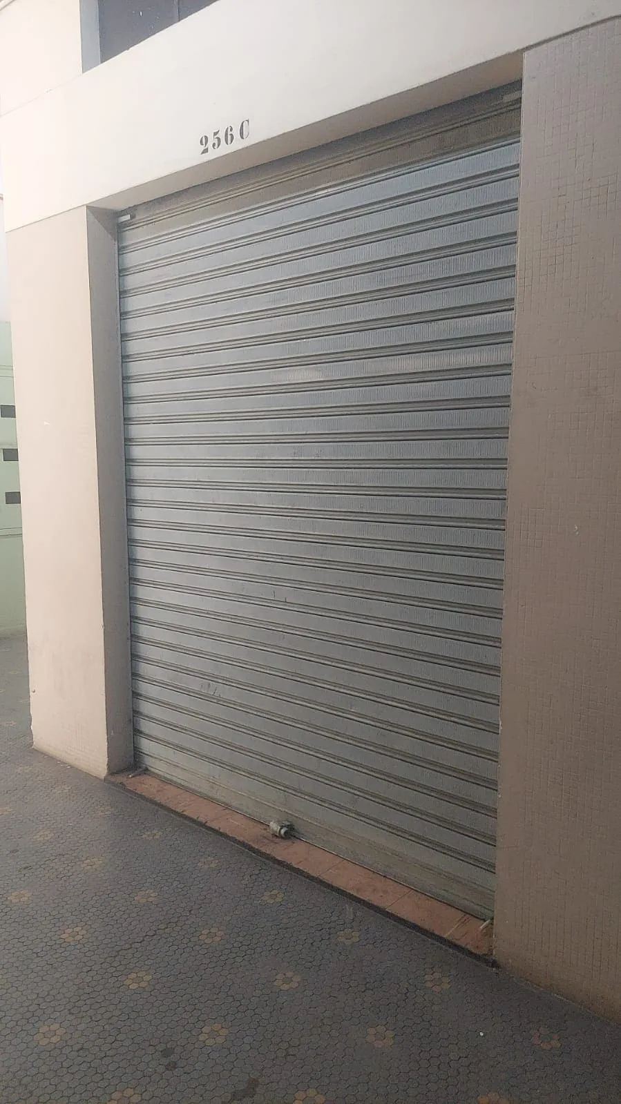 Porta de aço galvanizada fechada protegendo a entrada de um ponto comercial