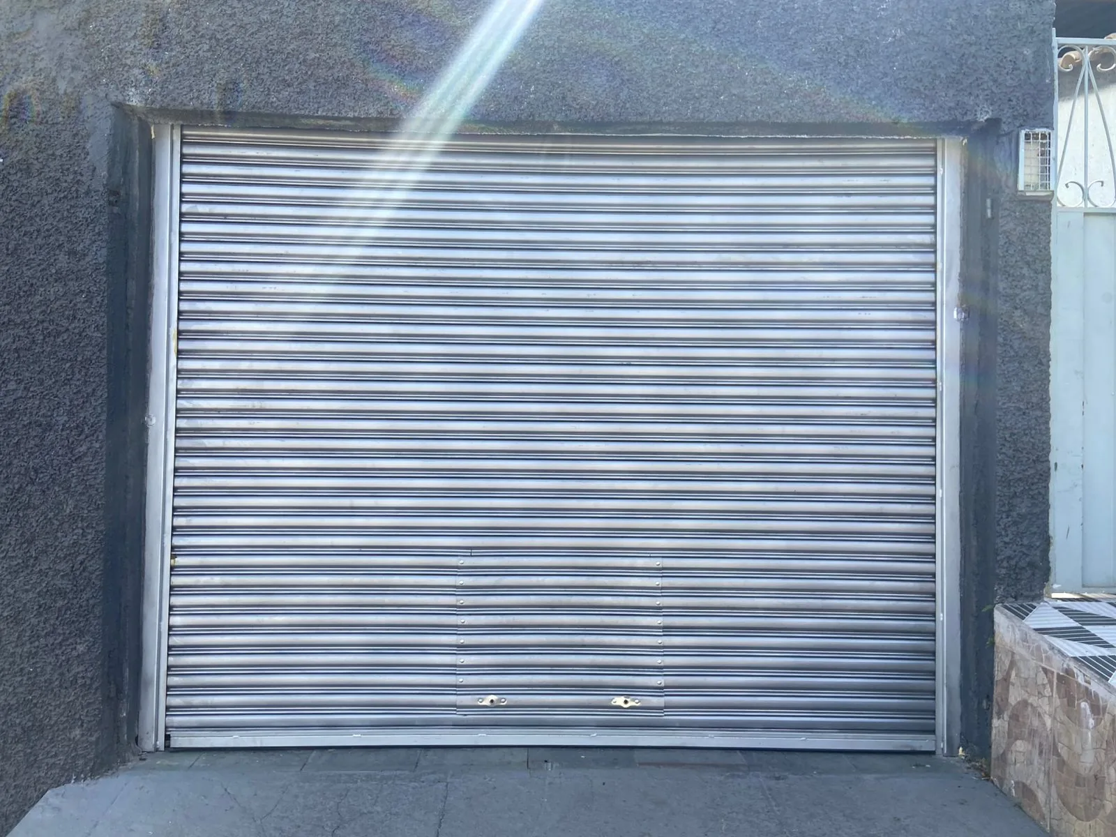 Porta de aço galvanizada de enrolar instalada em garagem residencial