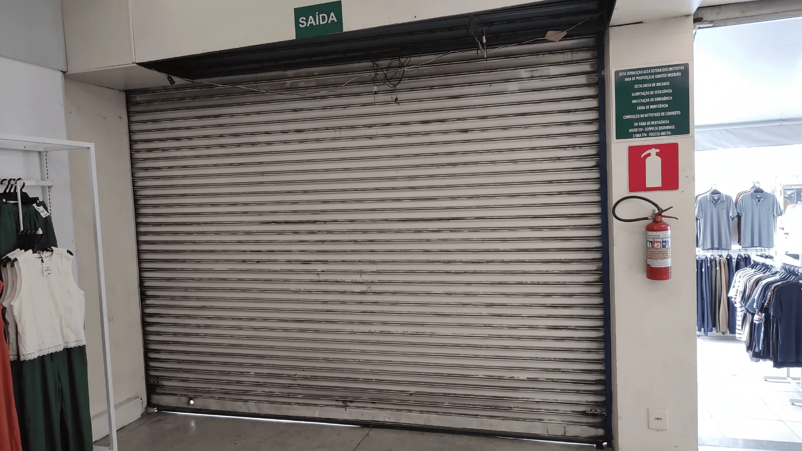 Porta de aço transvision perfurada instalada na entrada de loja de shopping