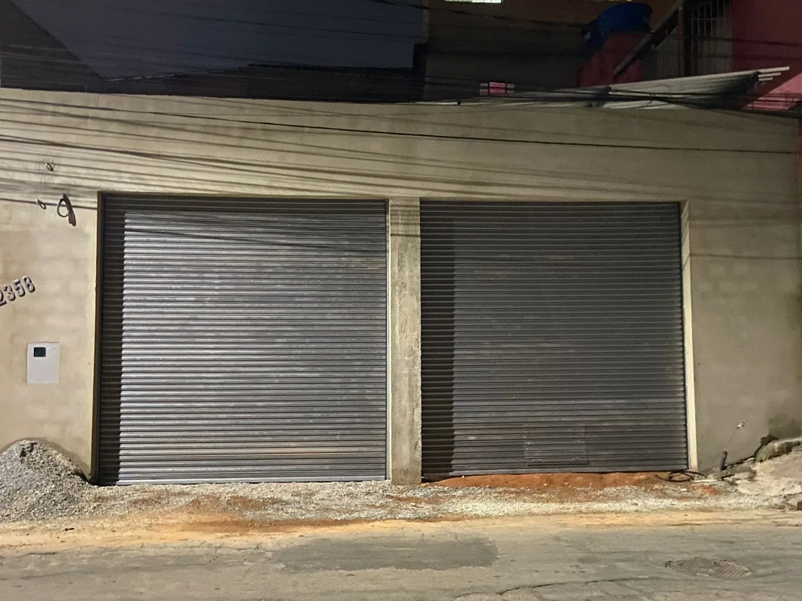 Par de portas de aço de enrolar fechadas em fachada comercial à noite