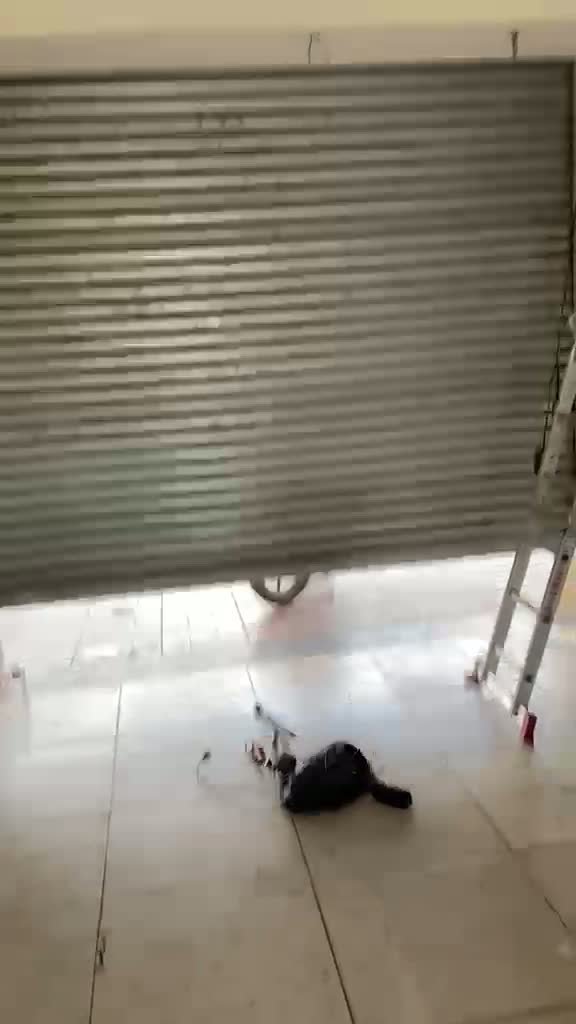 Serviço técnico em porta de enrolar de loja com a cortina parcialmente aberta
